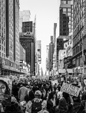 a crowd of people walking down a street next to tall buildings