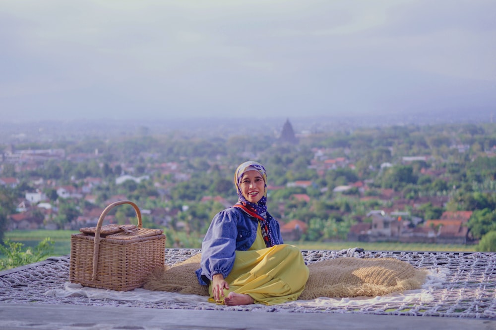 a woman sitting on top of a blanket next to a basket