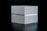 A minimalist gray box with a rectangular shape is placed on a dark surface. The lid and base are slightly separated, revealing a thin metallic interior. The lighting creates subtle shadows and highlights on the smooth surface of the box, giving it a sleek and modern appearance.