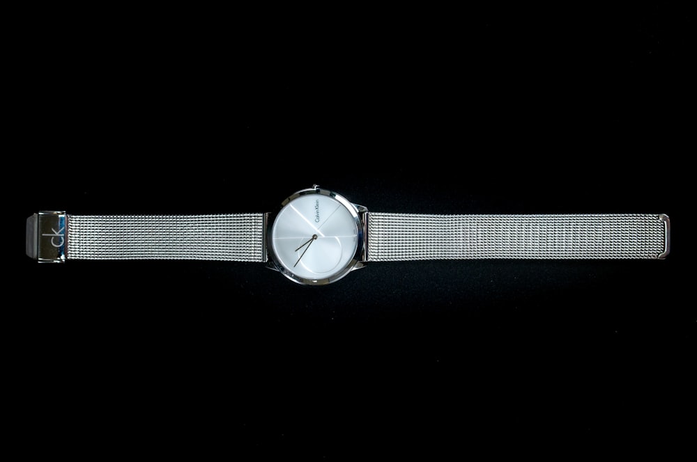 a watch with a mesh band on a black background