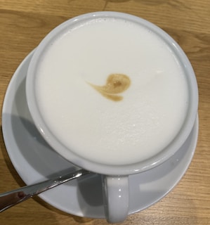 A frothy cappuccino in a ceramic cup with latte art on the surface.