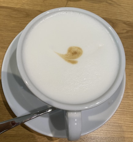 A frothy cappuccino in a ceramic cup with latte art on the surface.