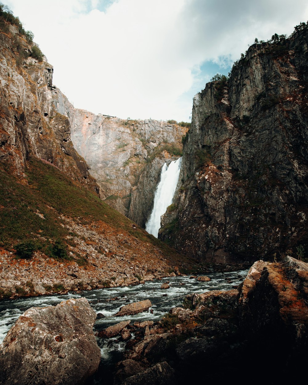 a mountain stream with a waterfall in the background