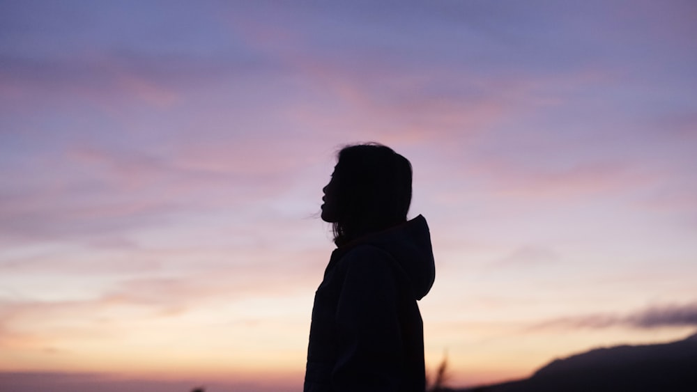 a silhouette of a person standing in front of a sunset