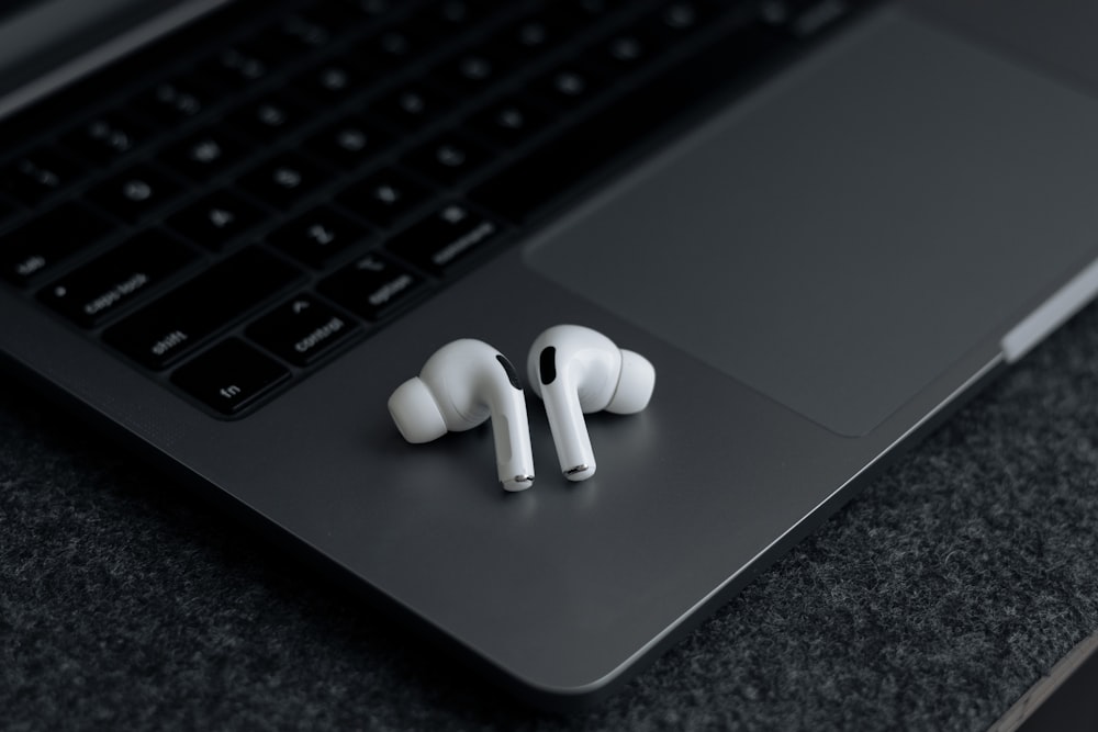 a pair of ear buds sitting on top of a laptop