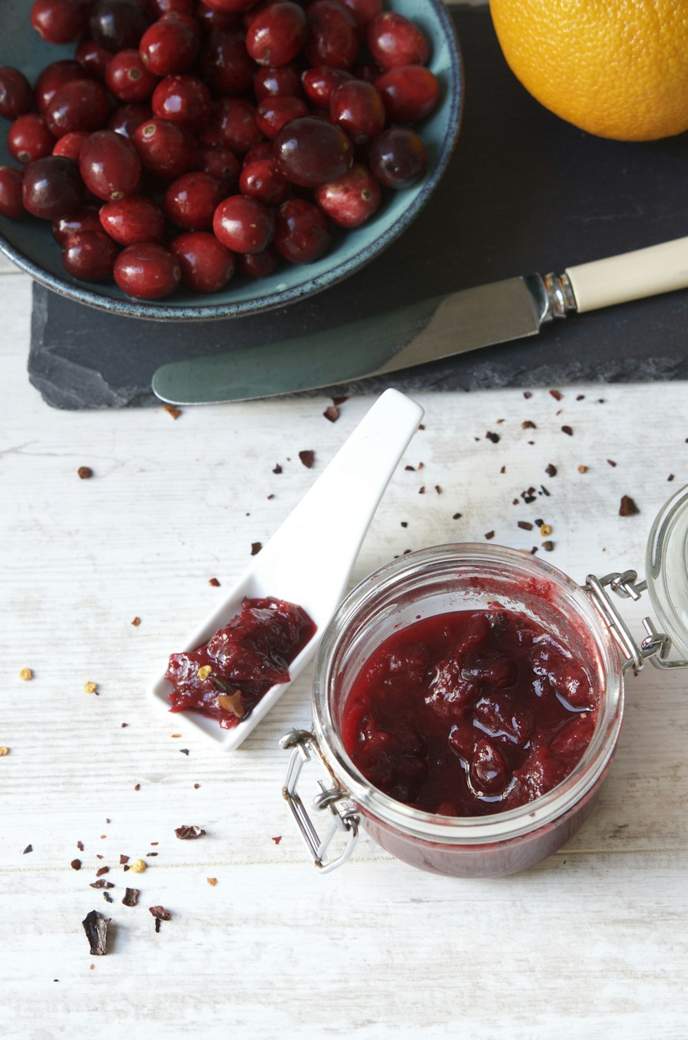 um frasco de molho de cranberry ao lado de uma tigela de cerejas