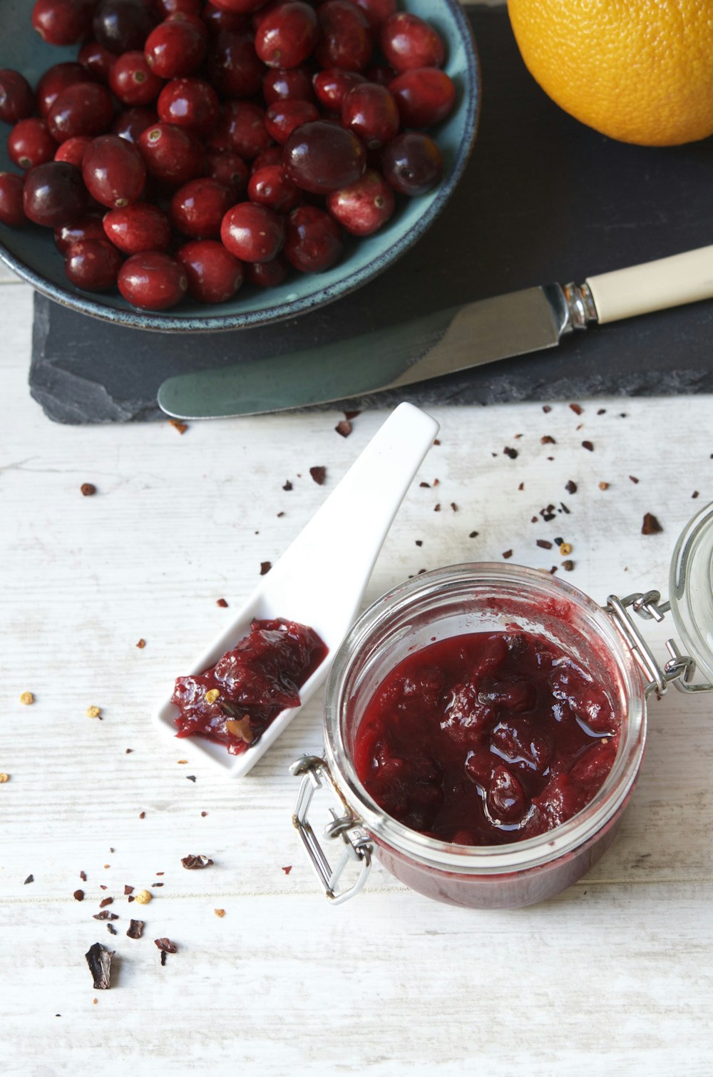 a jar of cranberry sauce next to a bowl of cherries