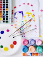 a white plate with paint and paintbrushes next to a white paper plate with