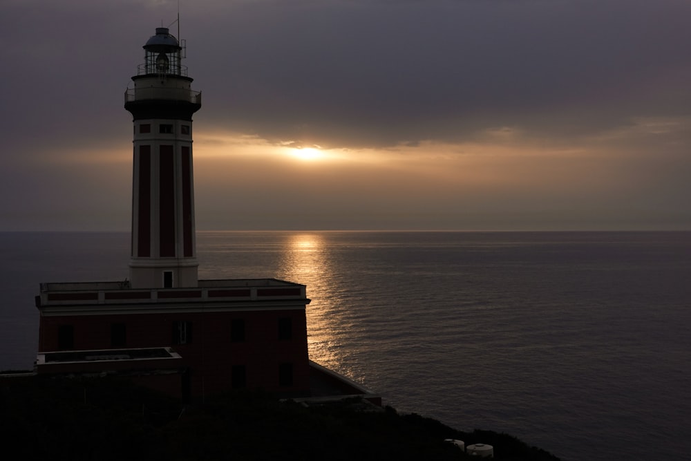 a lighthouse sitting on top of a cliff next to the ocean