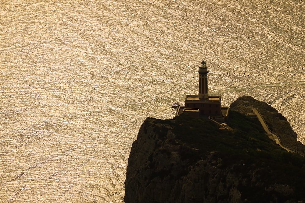 a lighthouse on top of a small island in the middle of the ocean