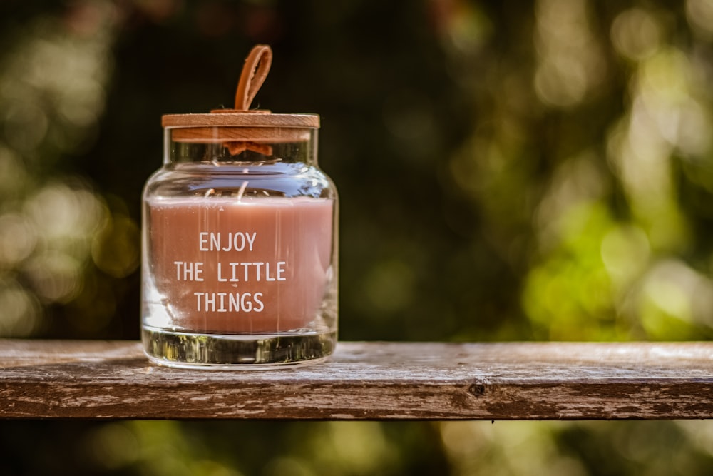 a glass jar with a message inside sitting on a wooden table