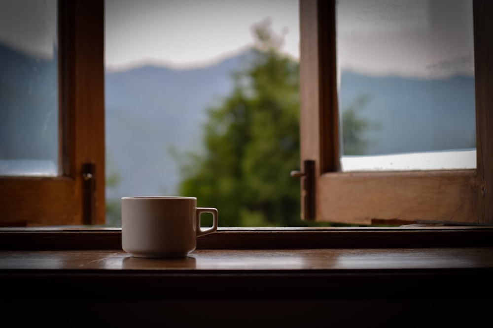 a cup sitting on a window sill in front of a window