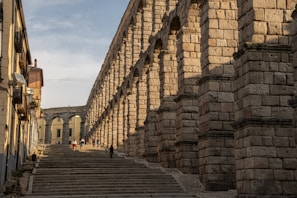 Exterior view of the Acueducto de San Lázaro with the apartamentos in the foreground on a sunny day