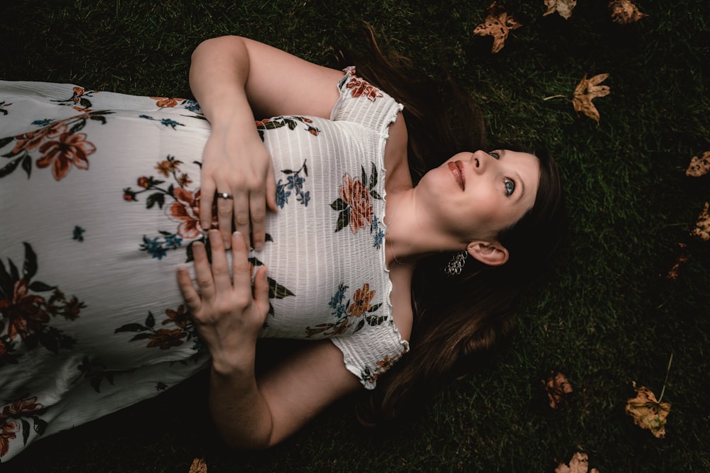 a woman laying in the grass with her hands on her chest