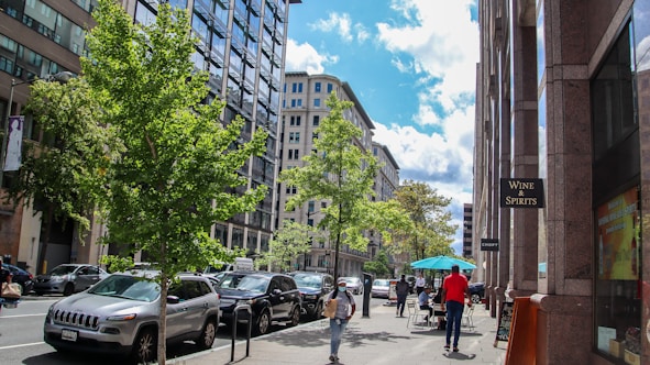 a group of people walking down a street next to tall buildings