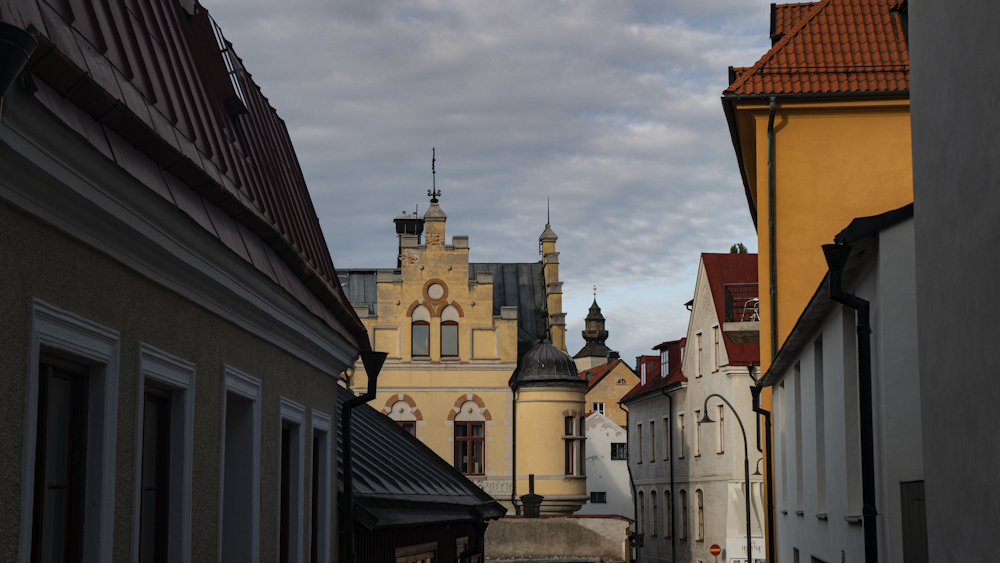 a narrow street with buildings and a clock tower in the background