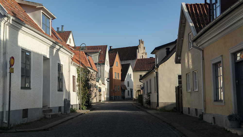 a narrow cobblestone street lined with white buildings