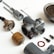 A collection of disassembled metallic mechanical parts arranged on a white surface. The parts include various cylindrical components, screws, and a rusty circular gasket. The components vary in size and shape, with some showing signs of wear.