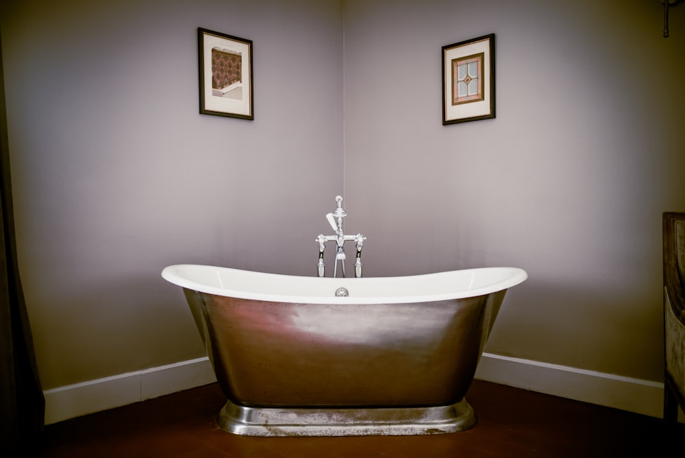 a bathroom with a claw foot tub and two framed pictures
