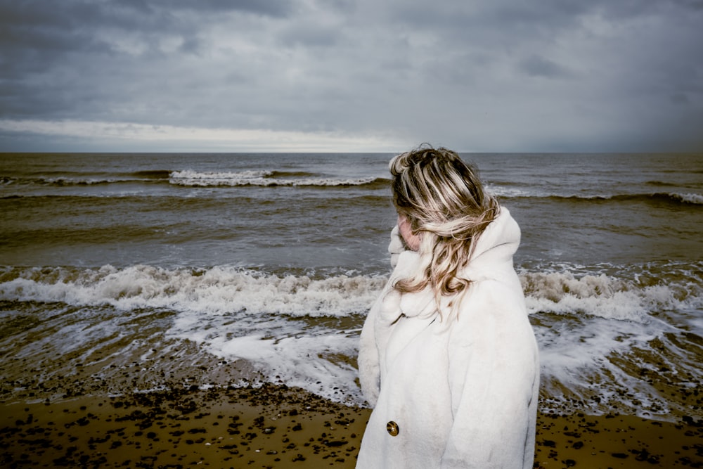 a woman standing on a beach next to the ocean