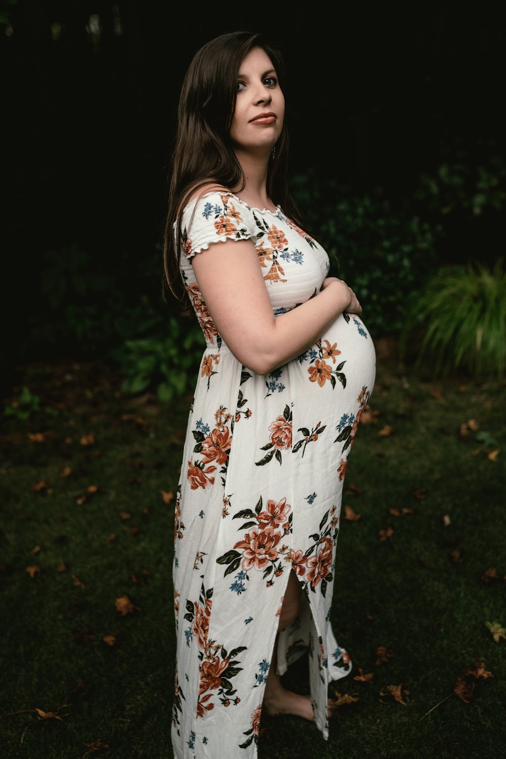 a pregnant woman in a floral dress poses for a photo