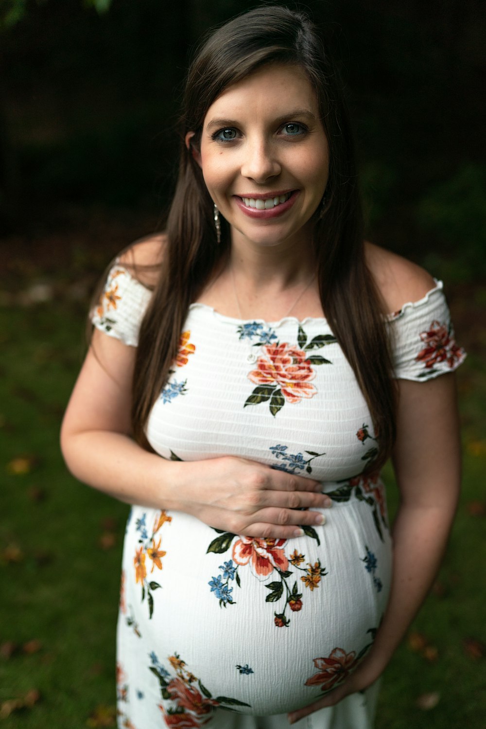 a pregnant woman posing for a picture in a floral dress