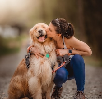 a woman kissing her dog on the cheek