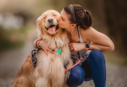 a woman kissing her dog on the cheek