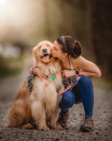 a woman kissing her dog on the cheek