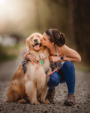 a woman kissing her dog on the cheek