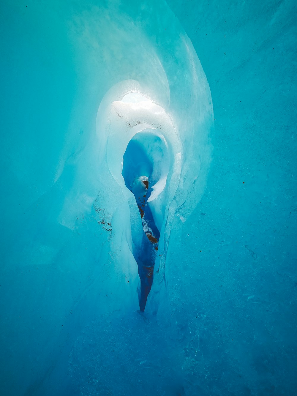 a man is swimming in a blue ice cave
