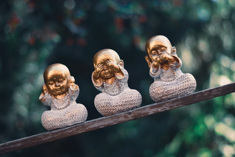 three golden buddha statues sitting on top of a wooden pole