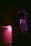 A dimly lit kitchen features a tiled backsplash illuminated by a purple light with a microwave oven above the countertop. The microwave's digital display reads 23:45, and the interior light casts an eerie silhouette of a hand on the microwave door.