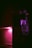 A dimly lit kitchen features a tiled backsplash illuminated by a purple light with a microwave oven above the countertop. The microwave's digital display reads 23:45, and the interior light casts an eerie silhouette of a hand on the microwave door.