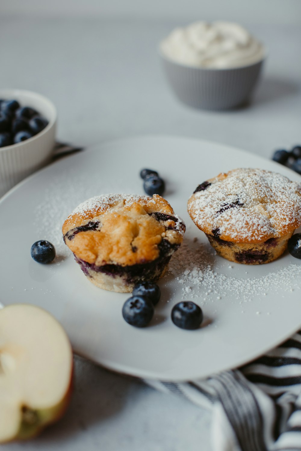 a white plate topped with two blueberry muffins