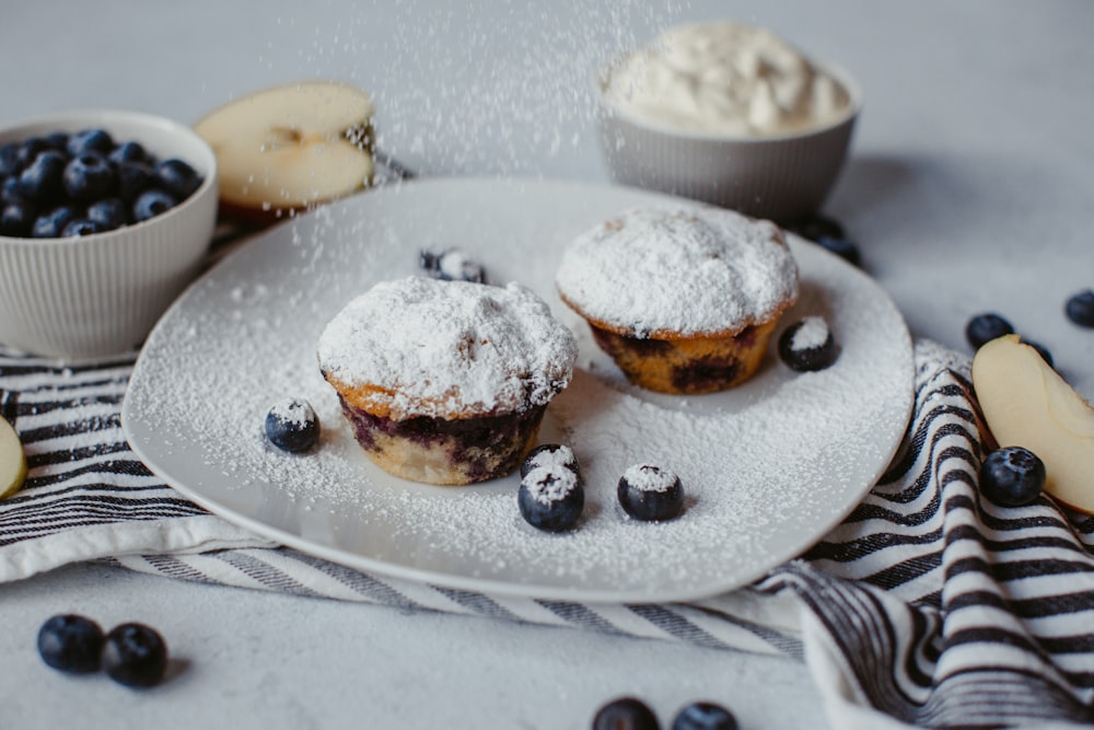 a white plate topped with blueberries covered in powdered sugar
