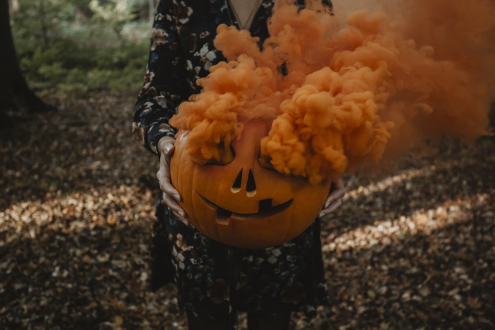 a person holding a pumpkin with smoke coming out of it