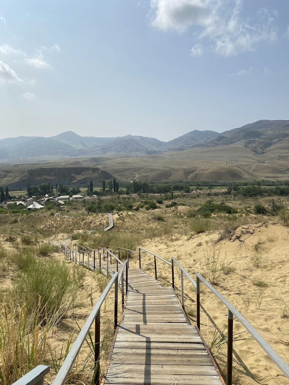a wooden walkway in the middle of a desert