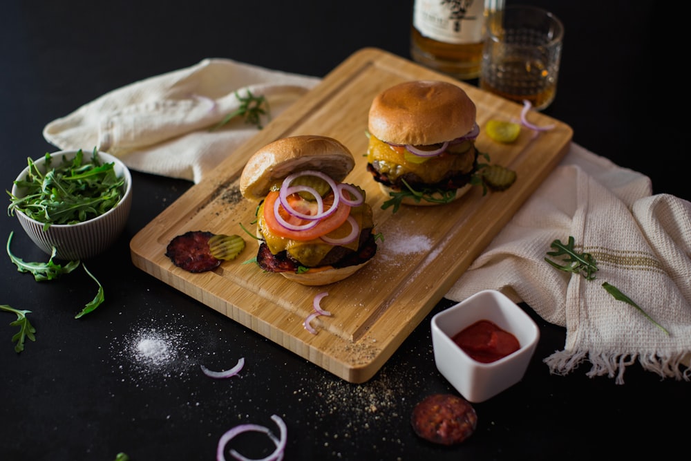 a couple of hamburgers sitting on top of a cutting board