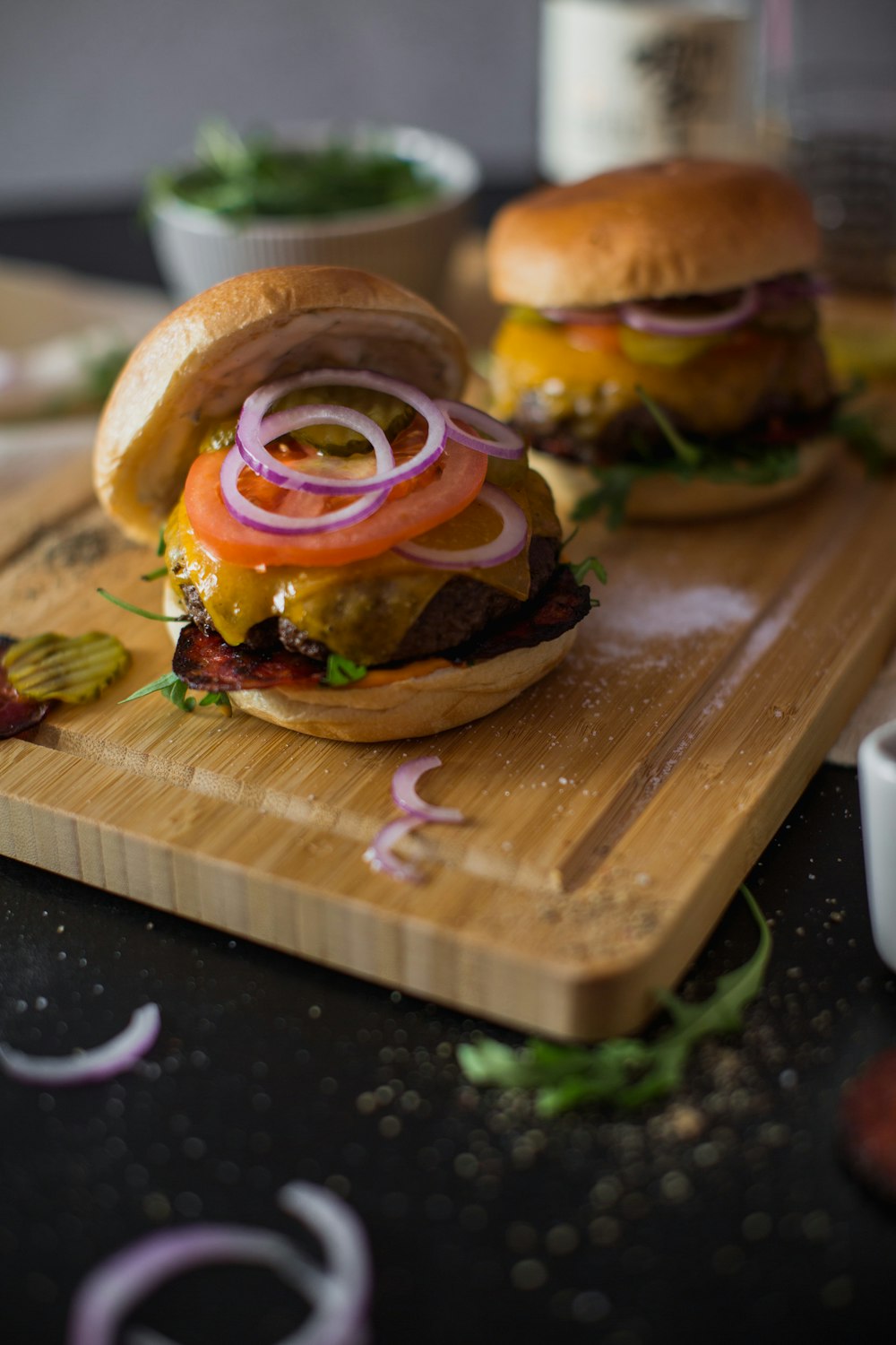 two hamburgers on a cutting board with onions