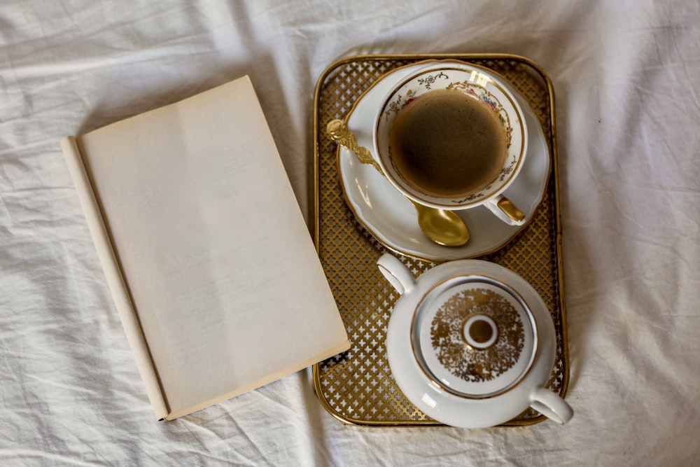 a cup of coffee and a book on a bed