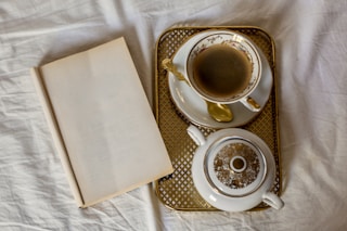 A coffee cup was placed next to a book on white sheets