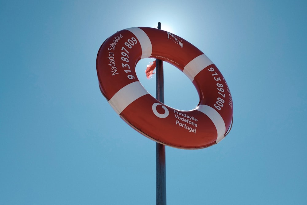 a red and white life preserver sitting on top of a pole