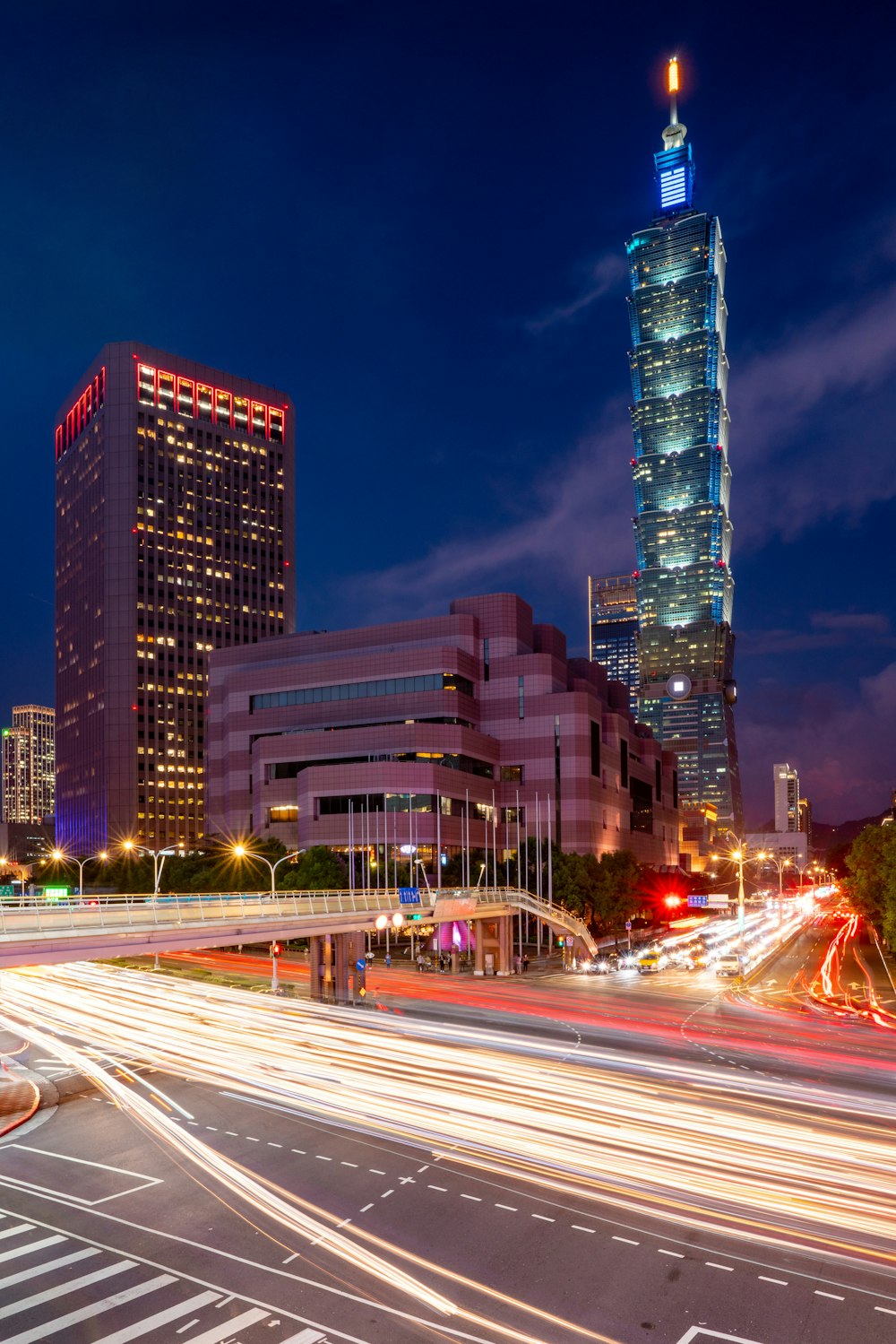 a city street at night with a very tall building in the background