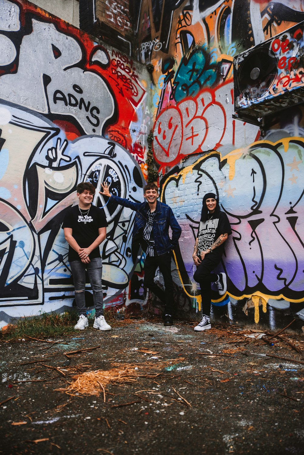 a group of young men standing next to a wall covered in graffiti