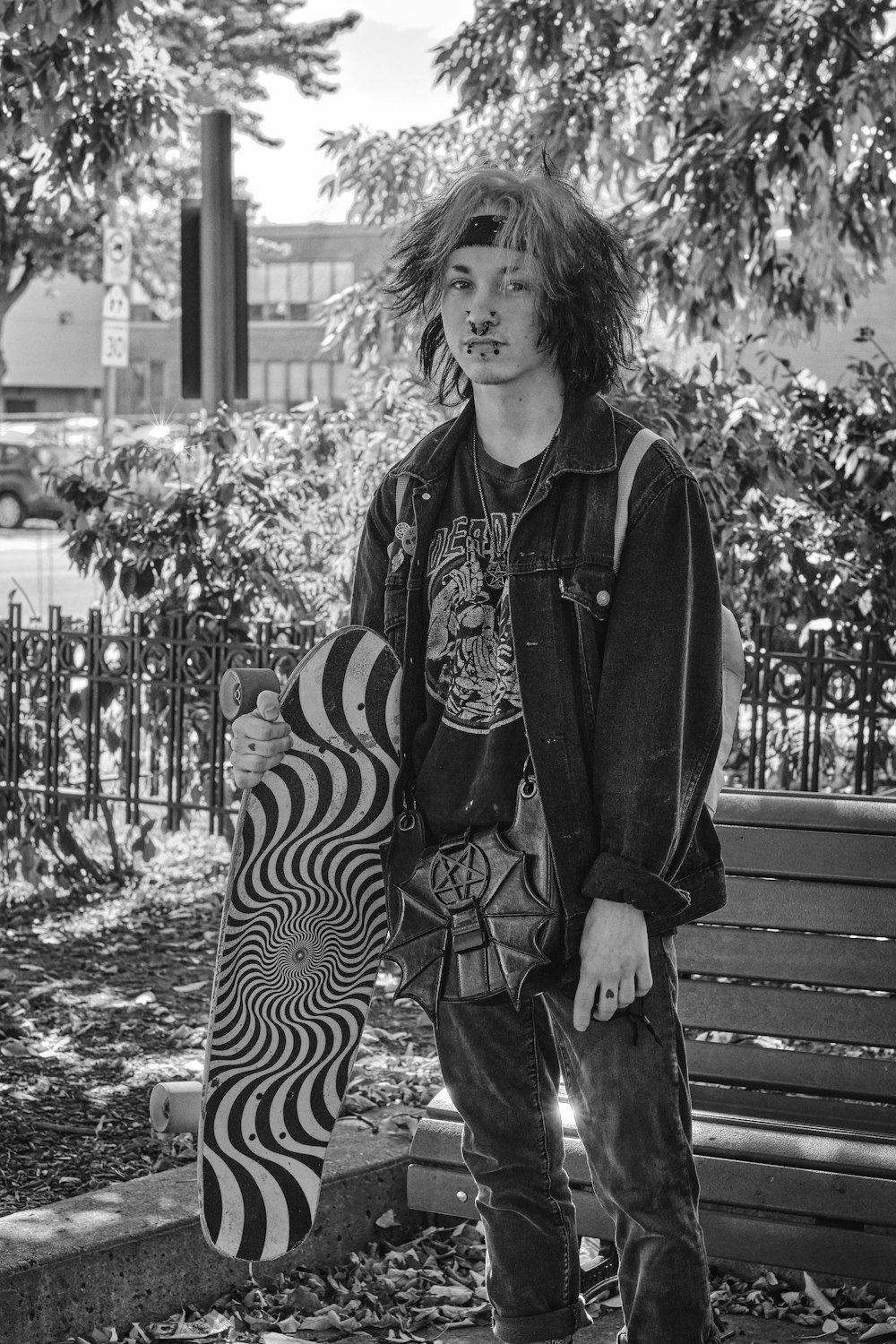 a young man holding a skateboard next to a park bench