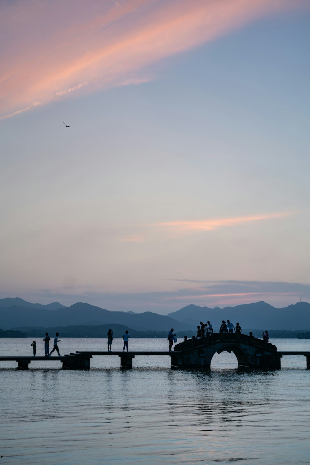 a group of people standing on a bridge over a body of water