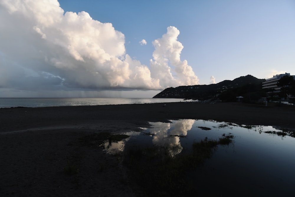 a beach with a body of water and clouds in the sky