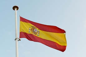 the spanish flag is flying high in the sky