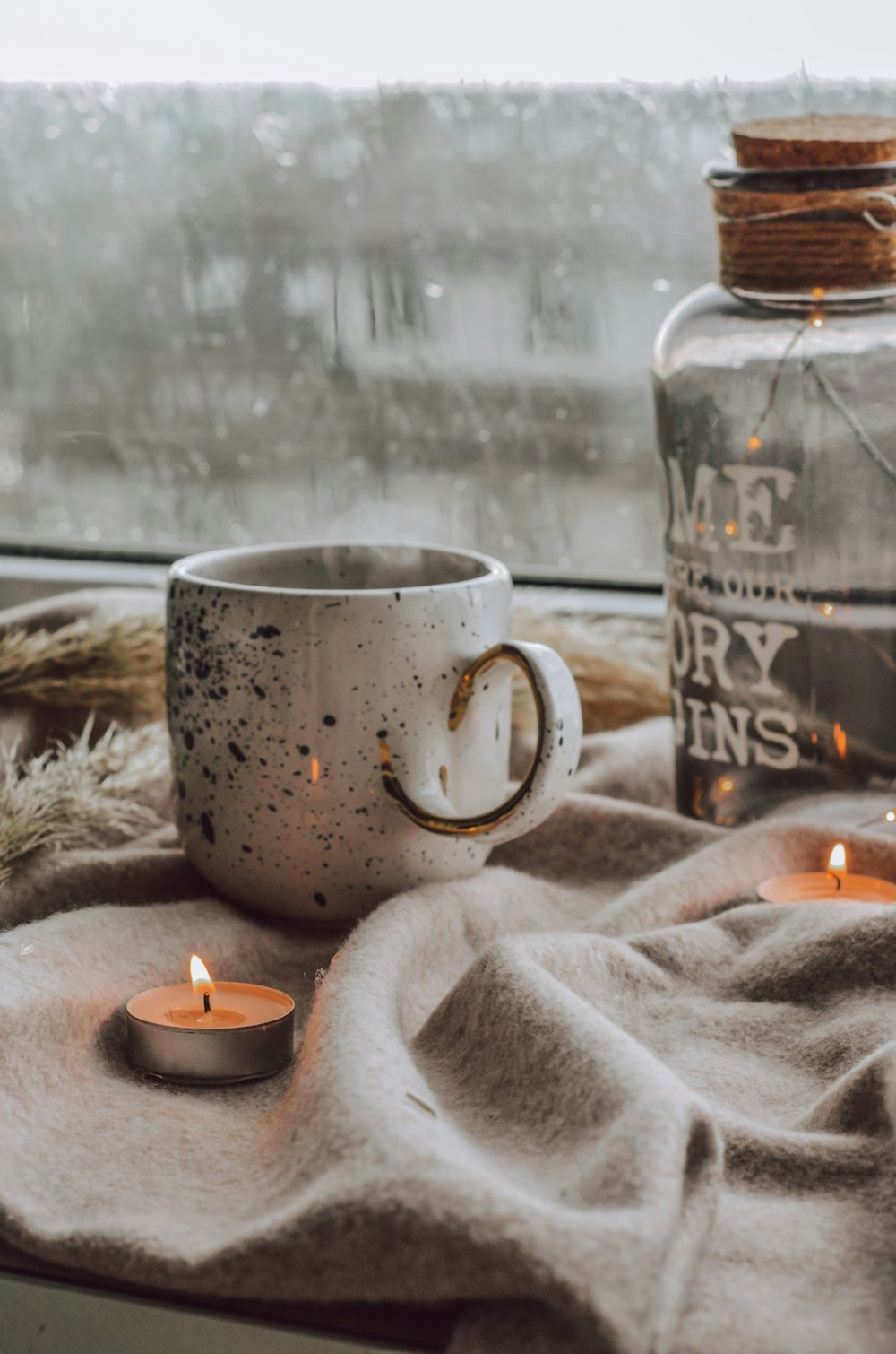 Una taza de café encima de una mesa junto a una ventana